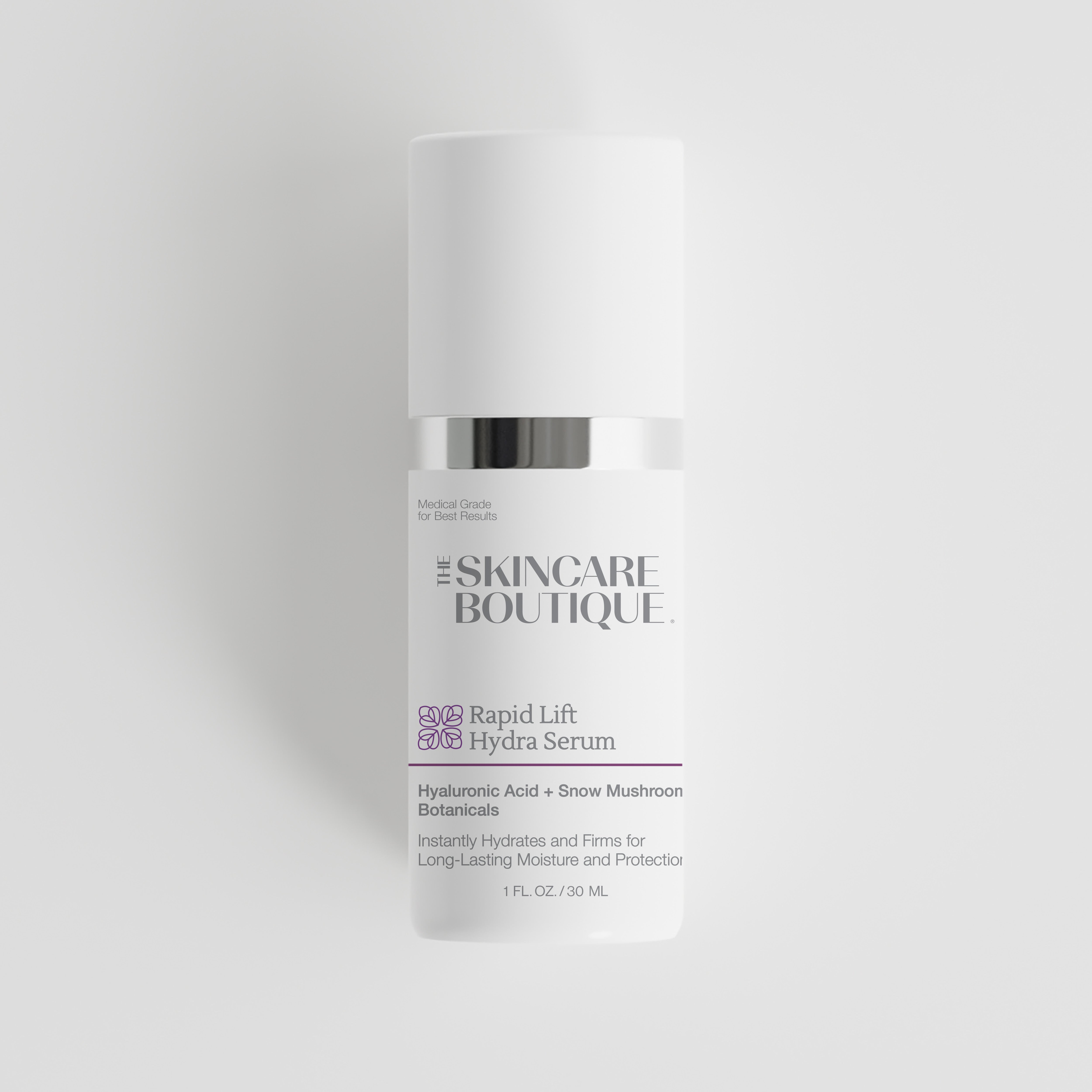 A white cylindrical skincare bottle with a silver band and a white cap, labeled 'The Skincare Boutique Rapid Lift Hydra Serum', centered on a light gray background.