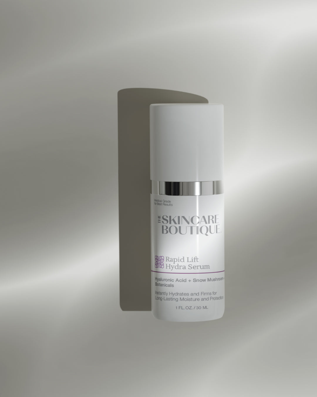 A white skincare pump bottle labeled 'SKINCARE BOUTIQUE Rapid Lift Hydra Serum' with a reflective silver band, shown against a soft gray gradient background with a soft shadow.