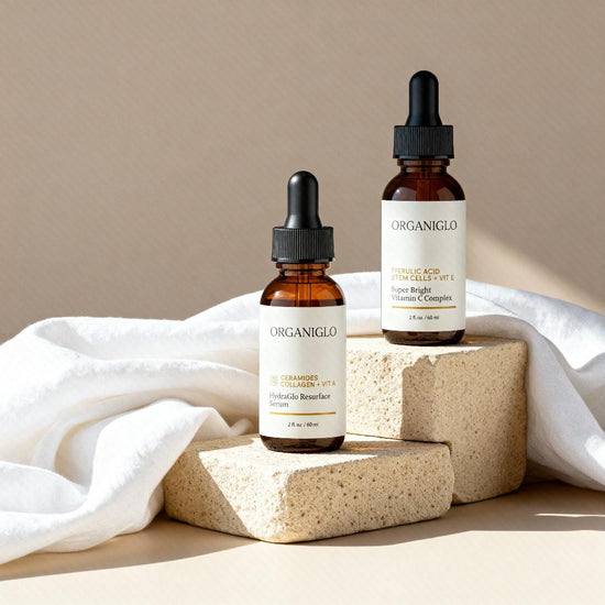 Two Organiglo skincare bottles with droppers on a beige background