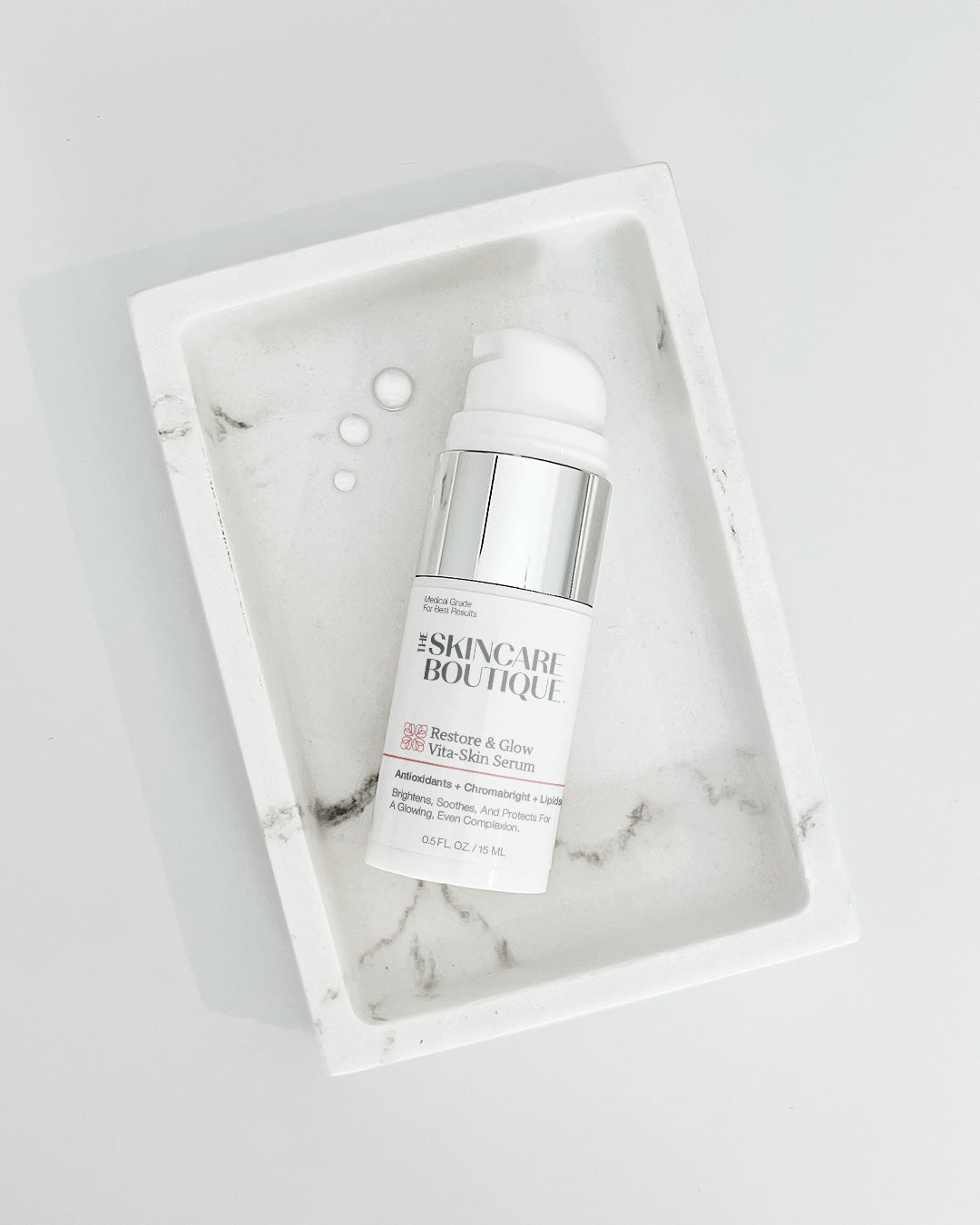 Skincare serum bottle in a marble-patterned box on a light gray background
