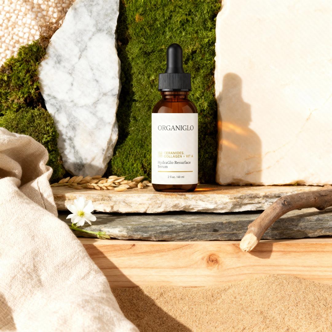 Organiglo skincare serum bottle on a natural wooden surface with stones and plants in the background