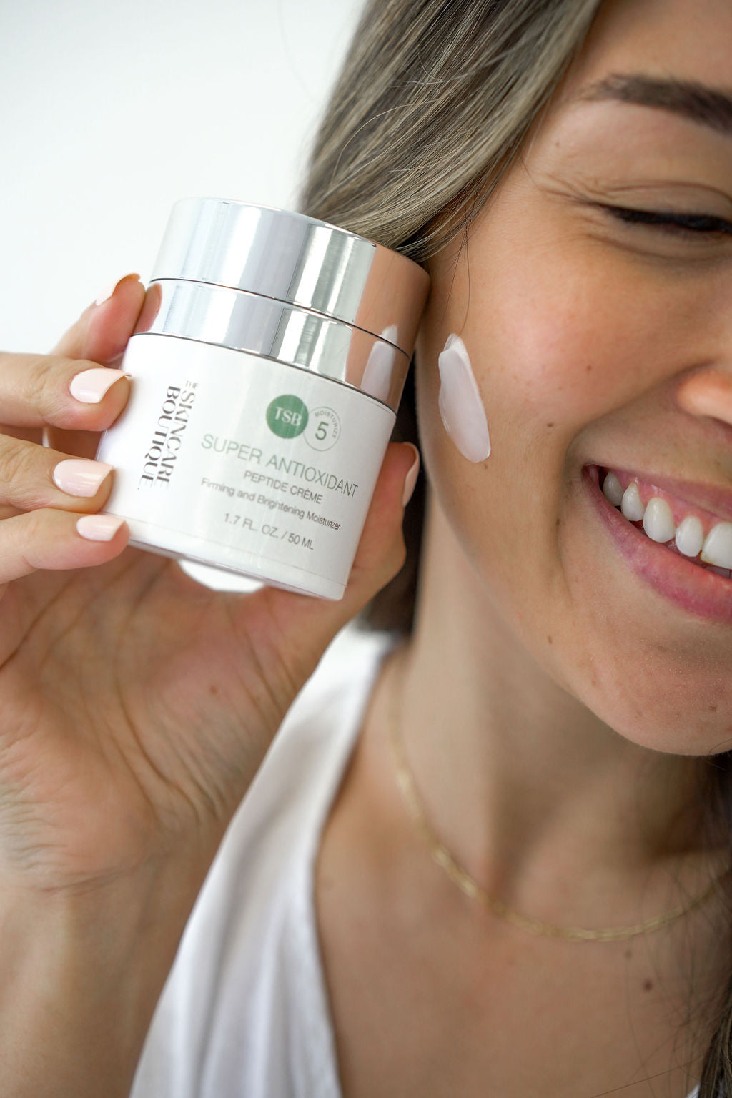 SUPER ANTIOXIDANT PEPTIDE CREME BEING HELD WITH SOMEONE SMILING